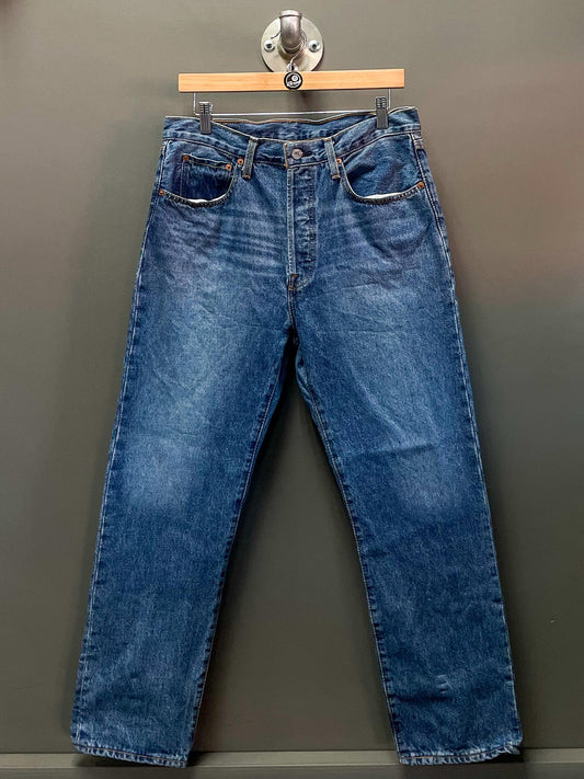 Blue jeans on a hanger against a gray background